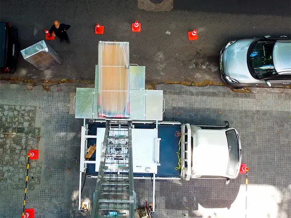 Plataforma de elevación mecánica de Empresa Dante iniciando la carga de mobiliario protegido en la vía pública de Montevideo.