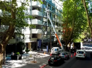 Elevador de altura mecánico trasladando muebles por el exterior de un edificio, evitando el uso de ascensores y pasillos estrechos.