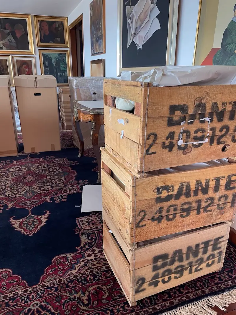 Cajones de madera de Empresa Dante apilados en un living con los muebles embalados y los cuadros apoyados contra la pared